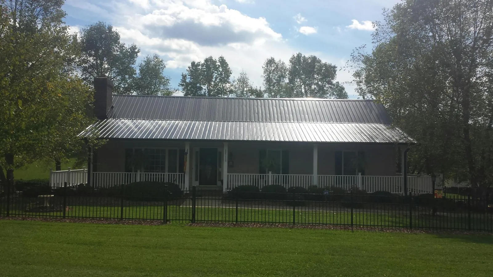 Gray metal roof on a brick ranch with a full width front porch — Gutter Guard Installation work by our crew in Collinsville